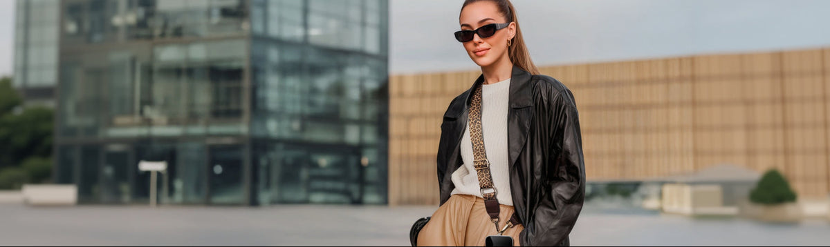 Frau trägt Smartphone-Hülle mit Leoparden-Handykette vor modernem Gebäude.