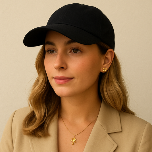 Frau mit schwarzer Cap und goldener Kette vor weißem Hintergrund.