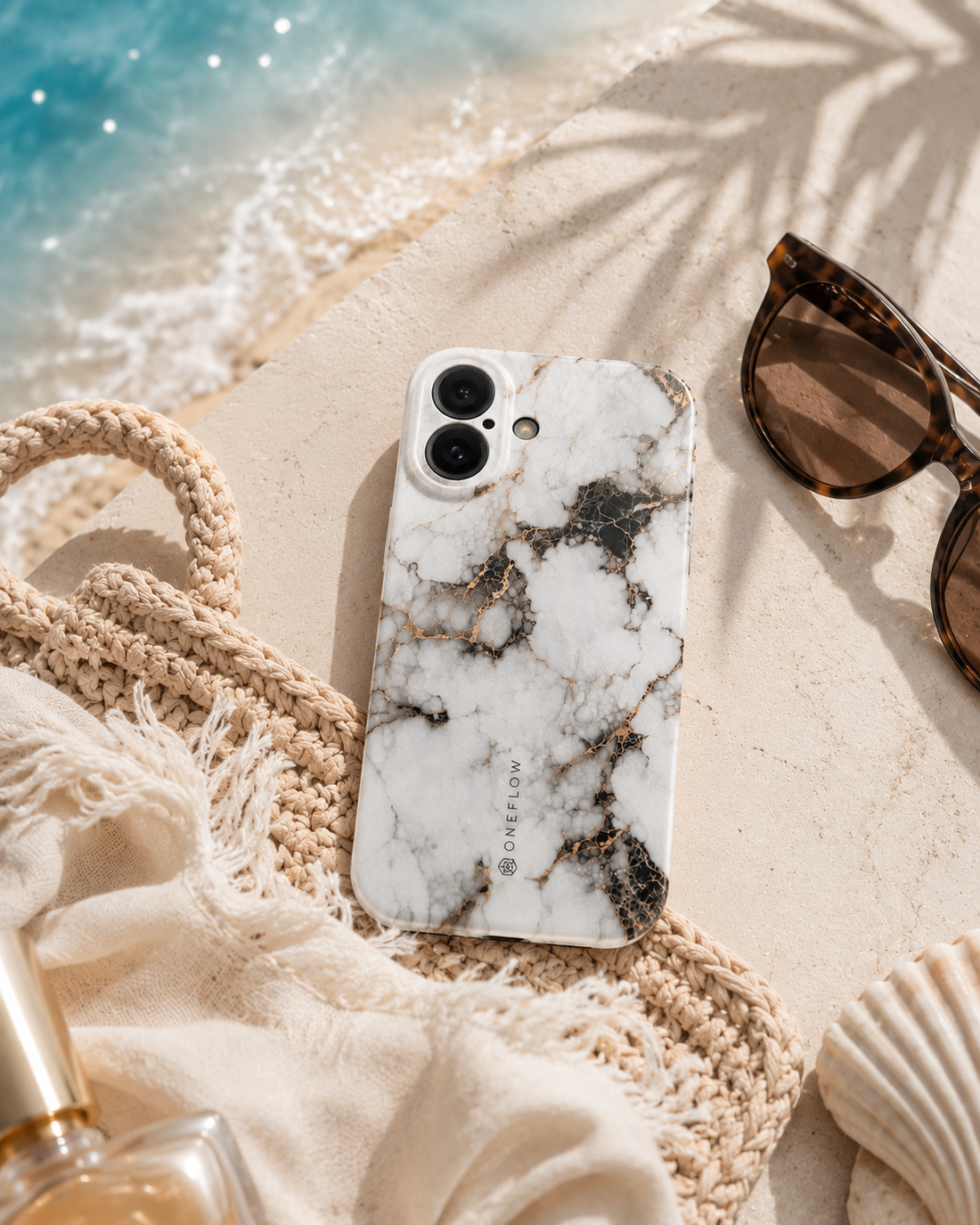 Smartphone-Hülle in Marmor-Optik neben Sonnenbrille am Strand.