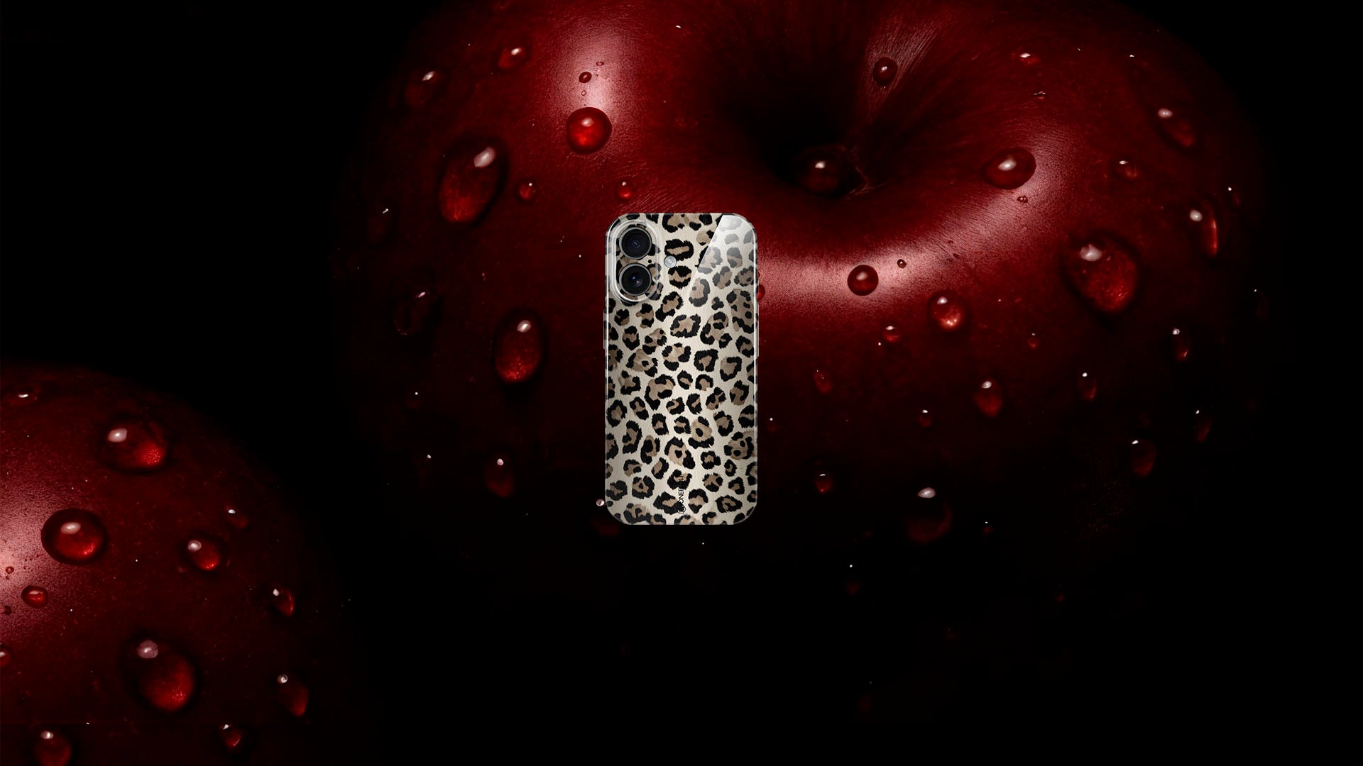Smartphone-Hülle mit Leopardenmuster vor rotem Apfel mit Wassertropfen.