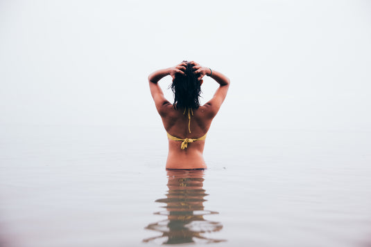 Mit dem Rücken zugekehrte Frau in Badebekleidung im Wasser.